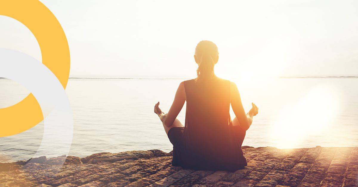 woman taking holiday booked through arrivia's employee loyalty and rewards platform is practicing mental health by meditating on the beach