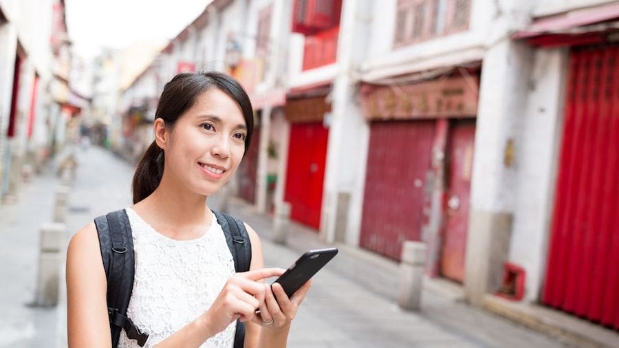 Young woman standing in the middle of the street while using mobile loyalty app