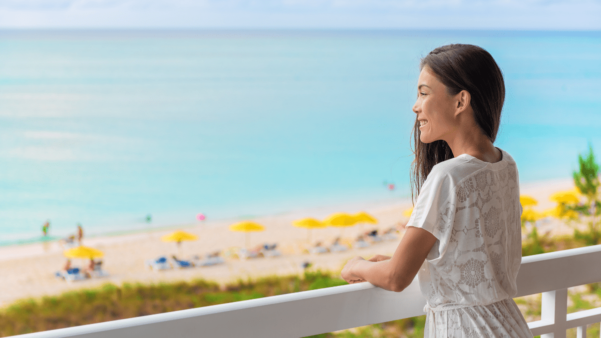 Woman standing on a timeshare balcony overlooking the beach