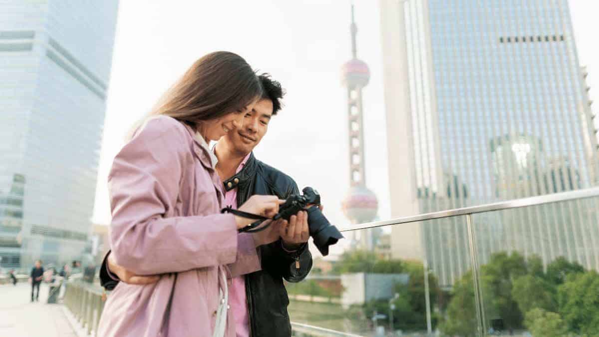 A couple creating unforgettable memories while adjusting a camera and sightseeing on vacation.
