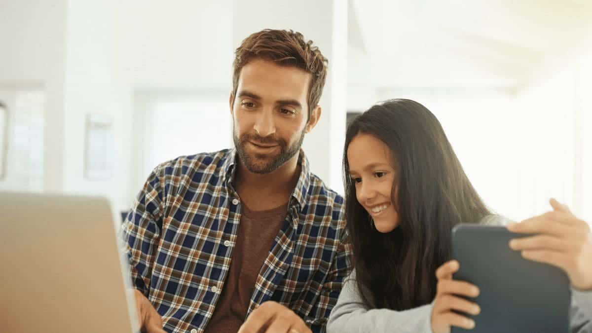 Gamification show with a shot of a young girl and her father using a tablet and laptop computer