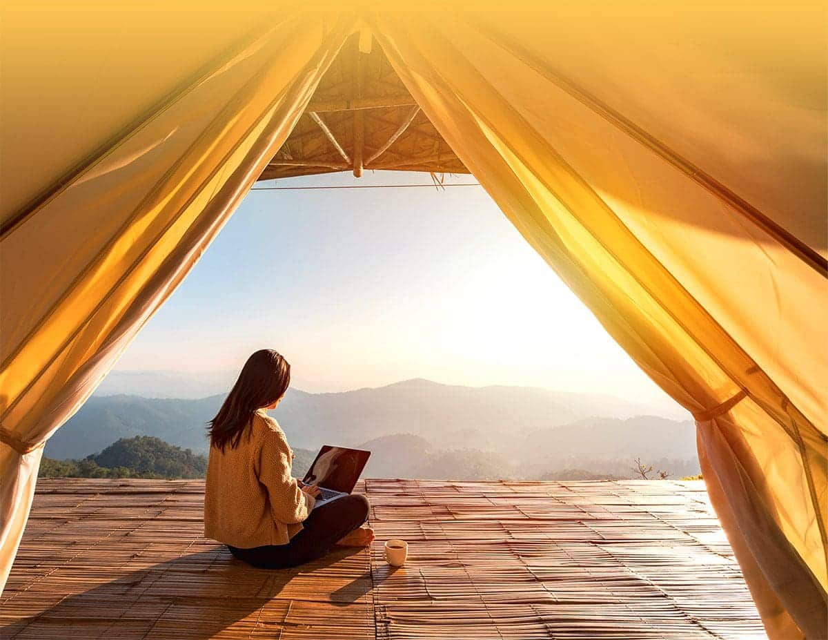 Girl working on her laptop outside her tent