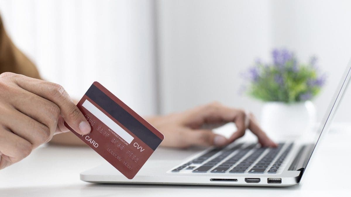 A hand using a laptop to shop with credit card rewards programs.