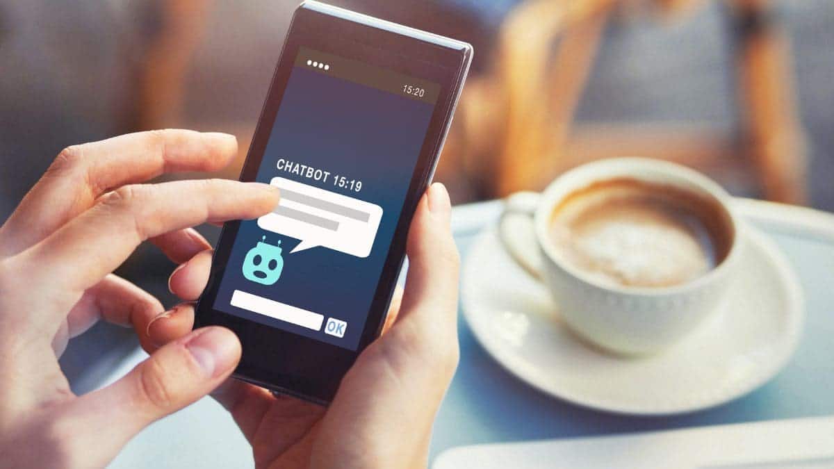 Hand using a cellphone with a screen showing chatbots in customer service.