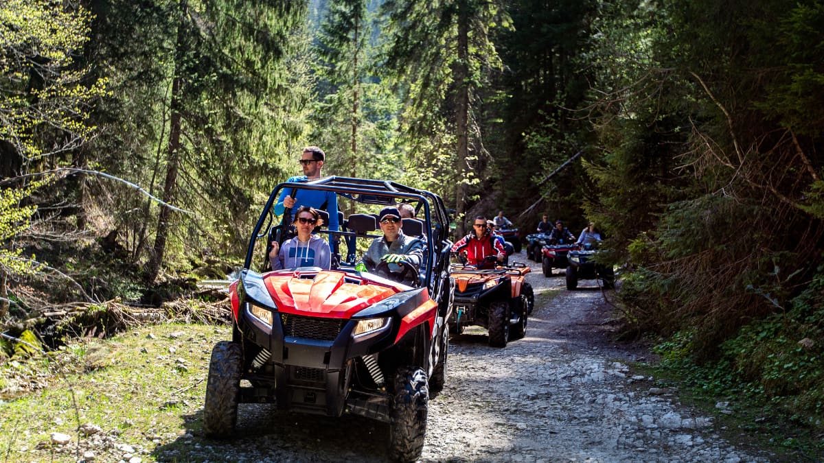 A tour group travels on ATVs and UTVs in the mountains booked using a paid loyalty program.