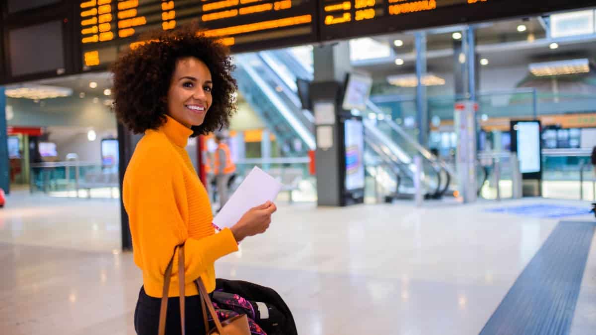 A woman standing before a departure sign at an airport.