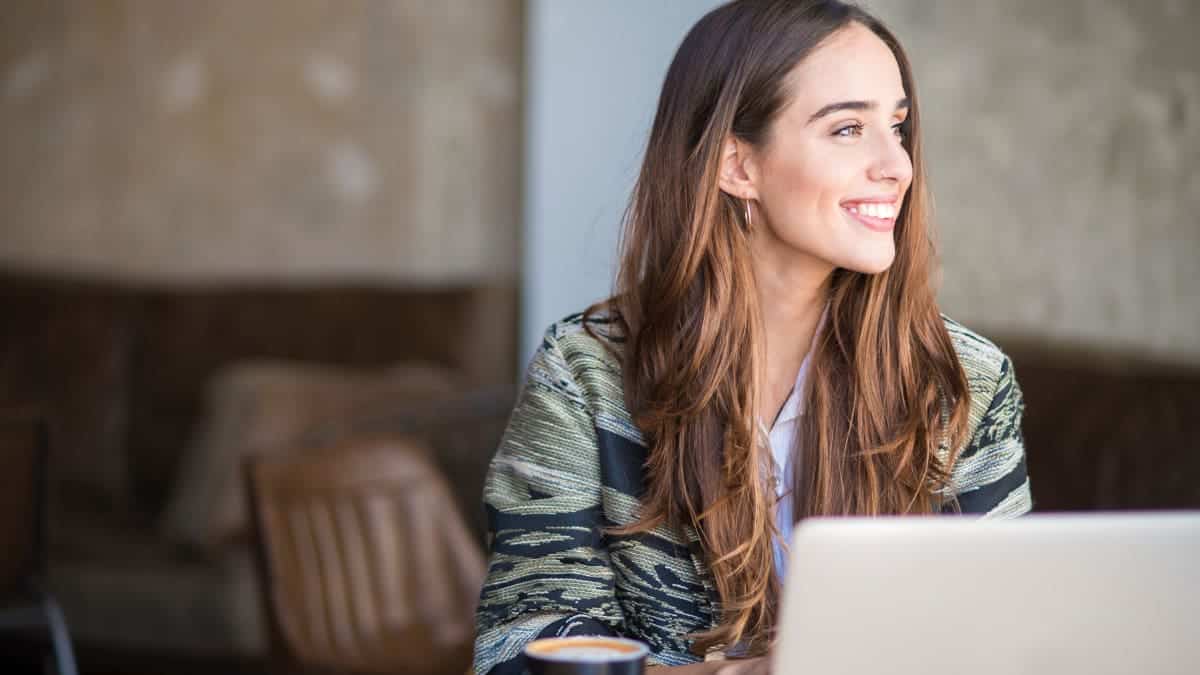 Smiling woman on the computer using a travel booking software platform.