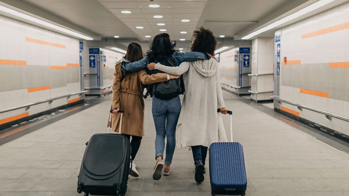 Three friends with suitcases travel together.