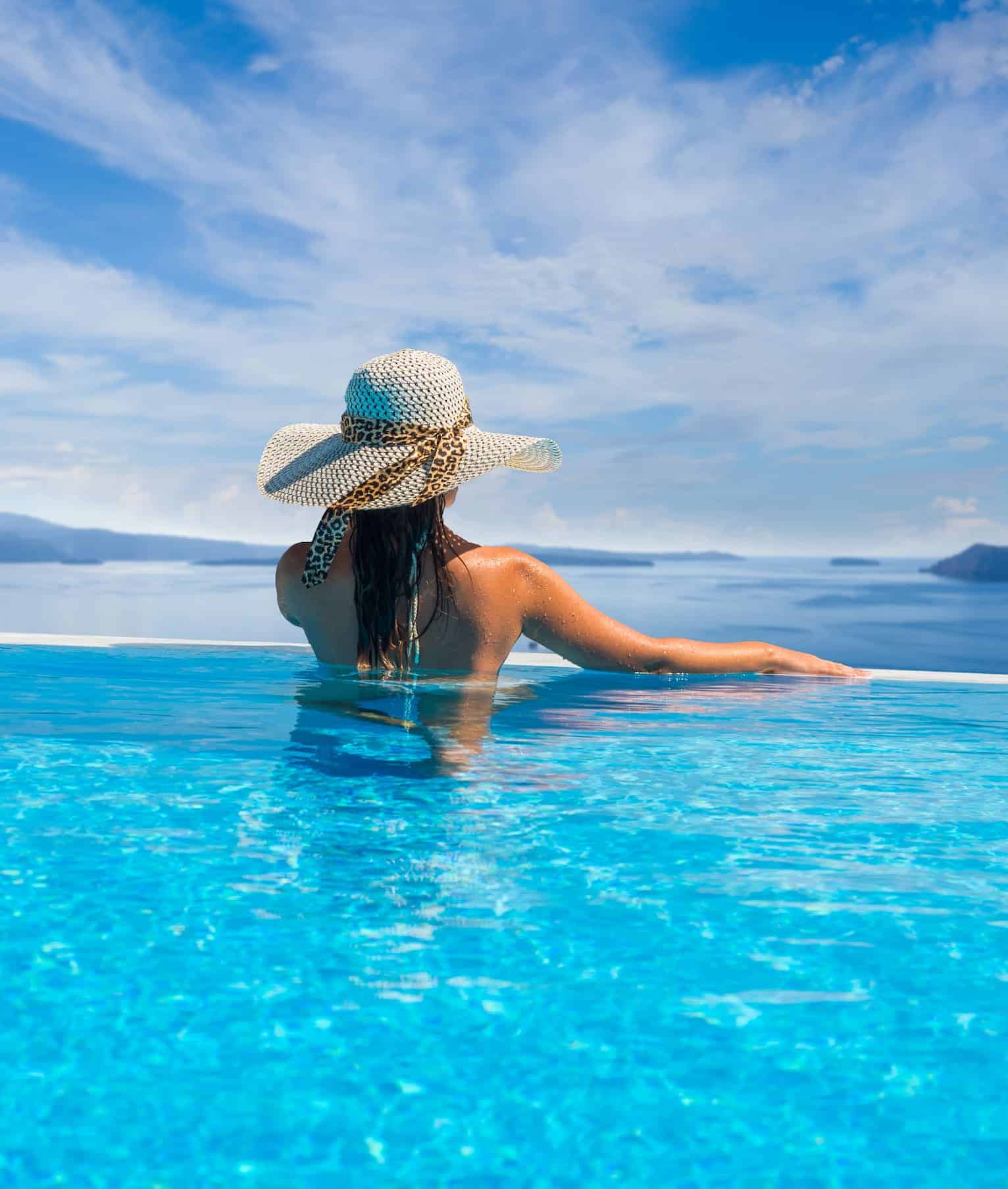 Woman enjoying relaxation in pool and looking at the view in Santorini Greece