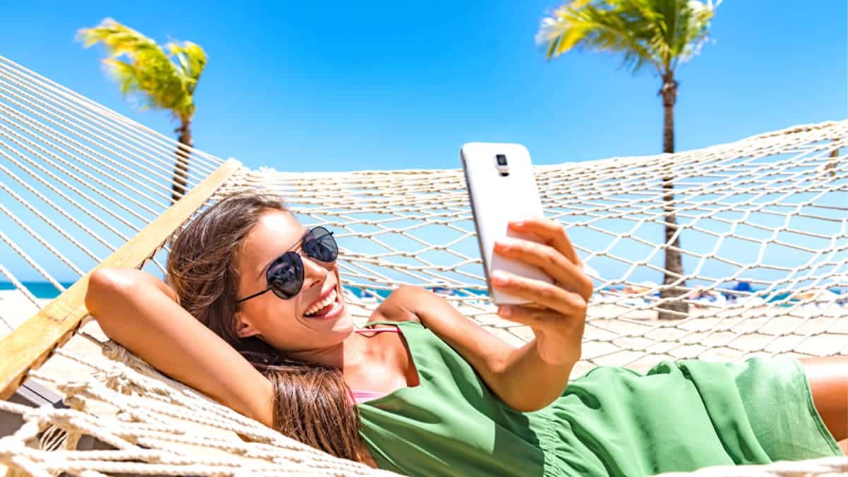 woman smiling at her phone because she just received travel rewards