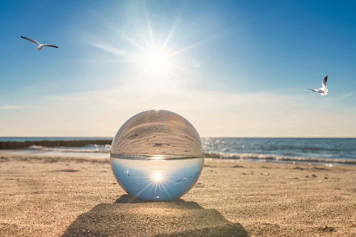 A crystal ball on a beautiful beach destination reflecting a beautiful shoreline.