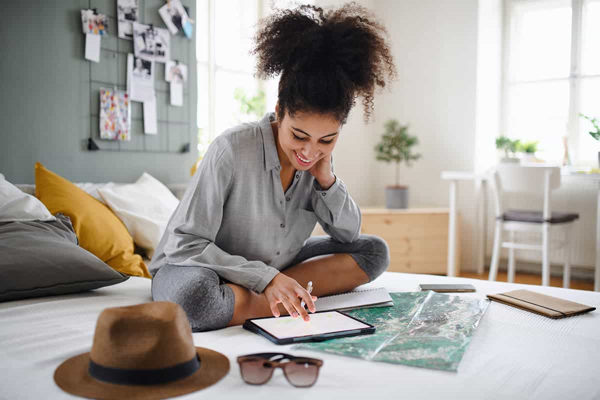 A woman sits on her bed planning a trip with artificial intelligence (AI)