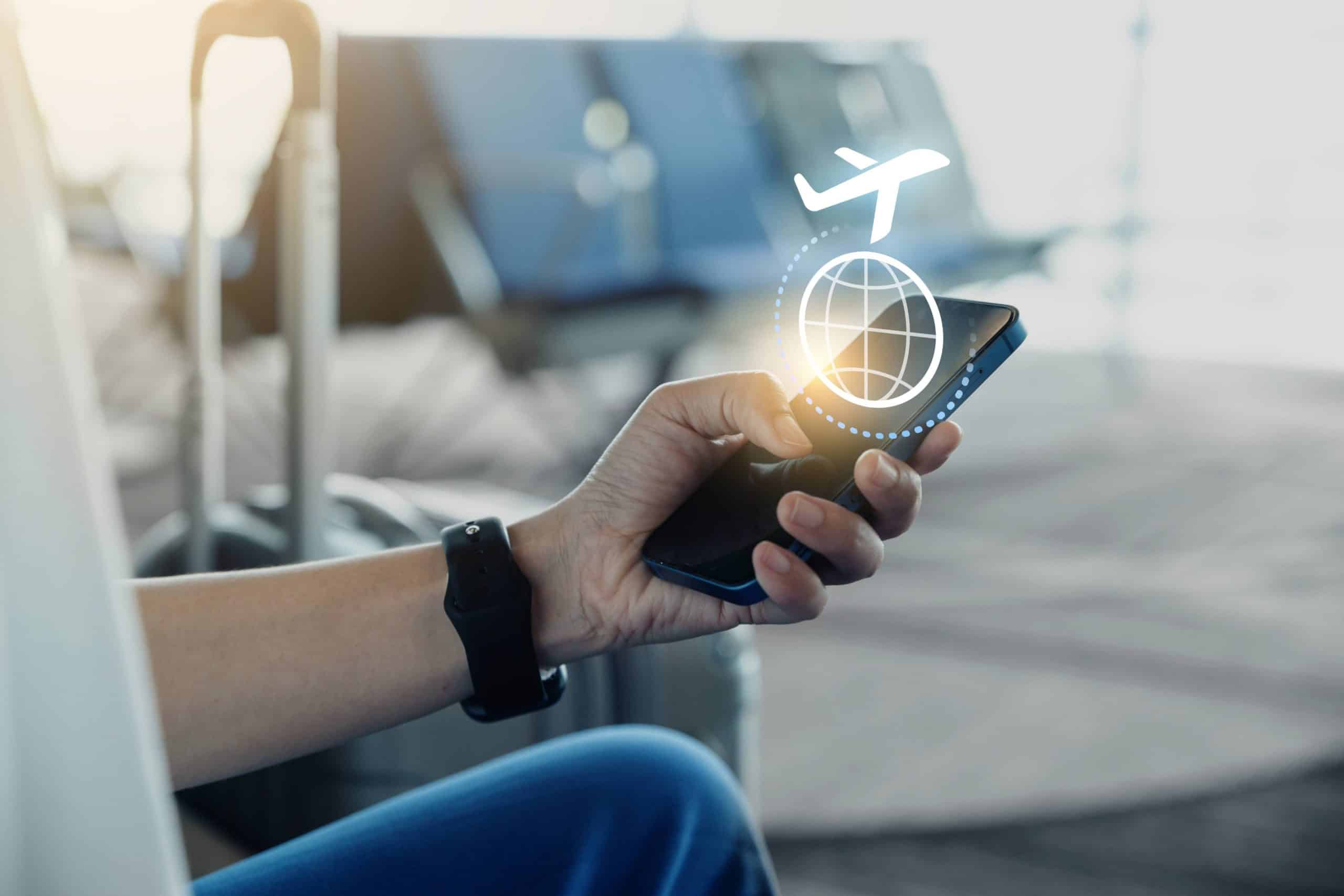 Traveler using smartphone for accommodation booking software at airport, illustrating mobile-first travel and loyalty integration