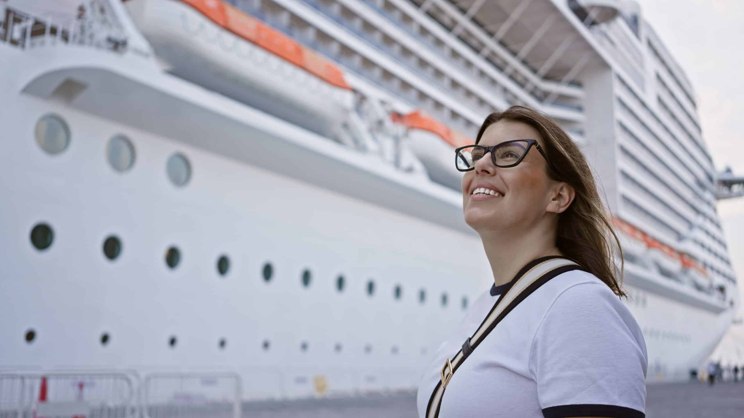 Smiling woman standing near a large white cruise ship