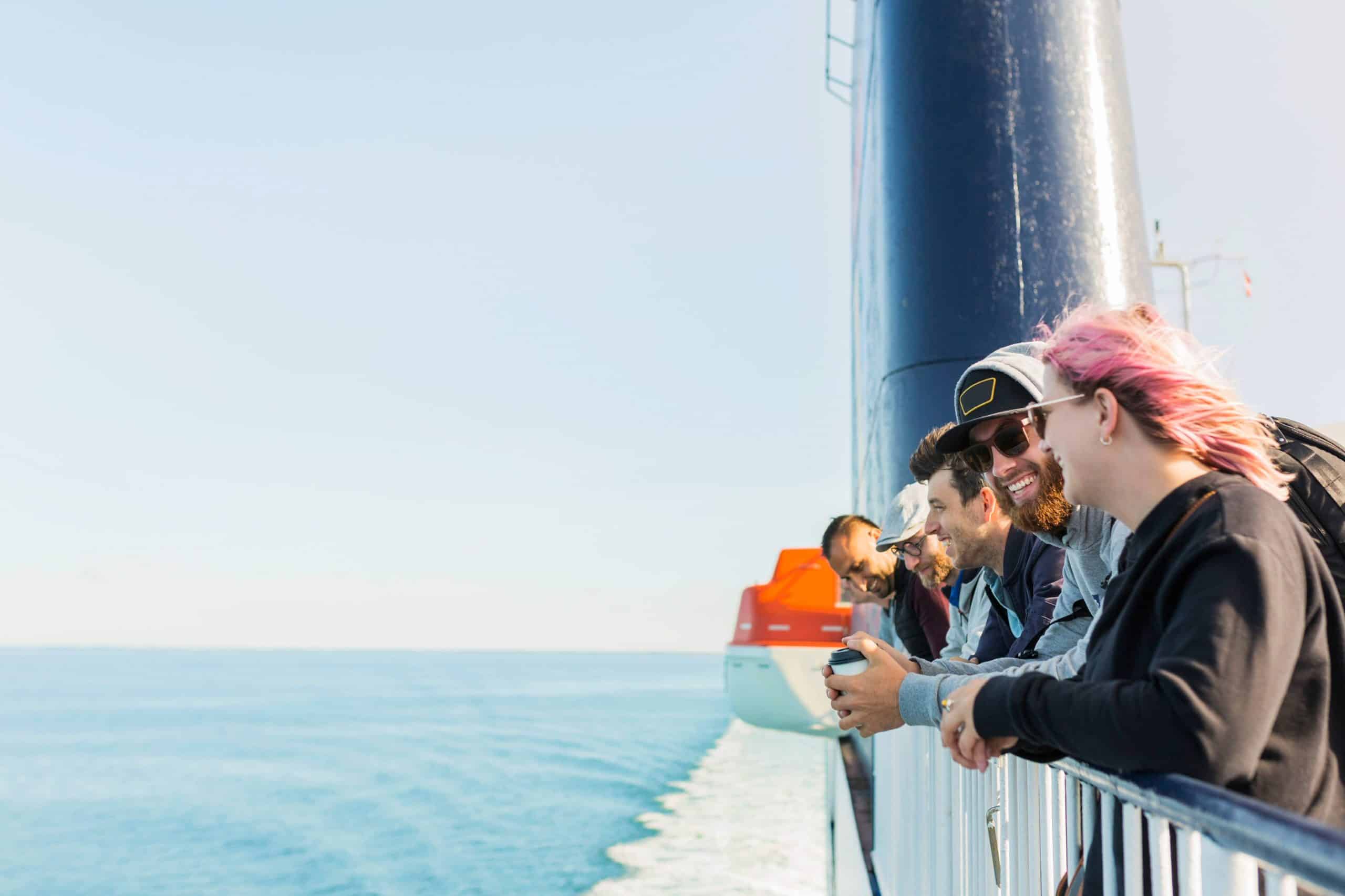 Group of friends smiling and enjoying the view from a cruise ship deck