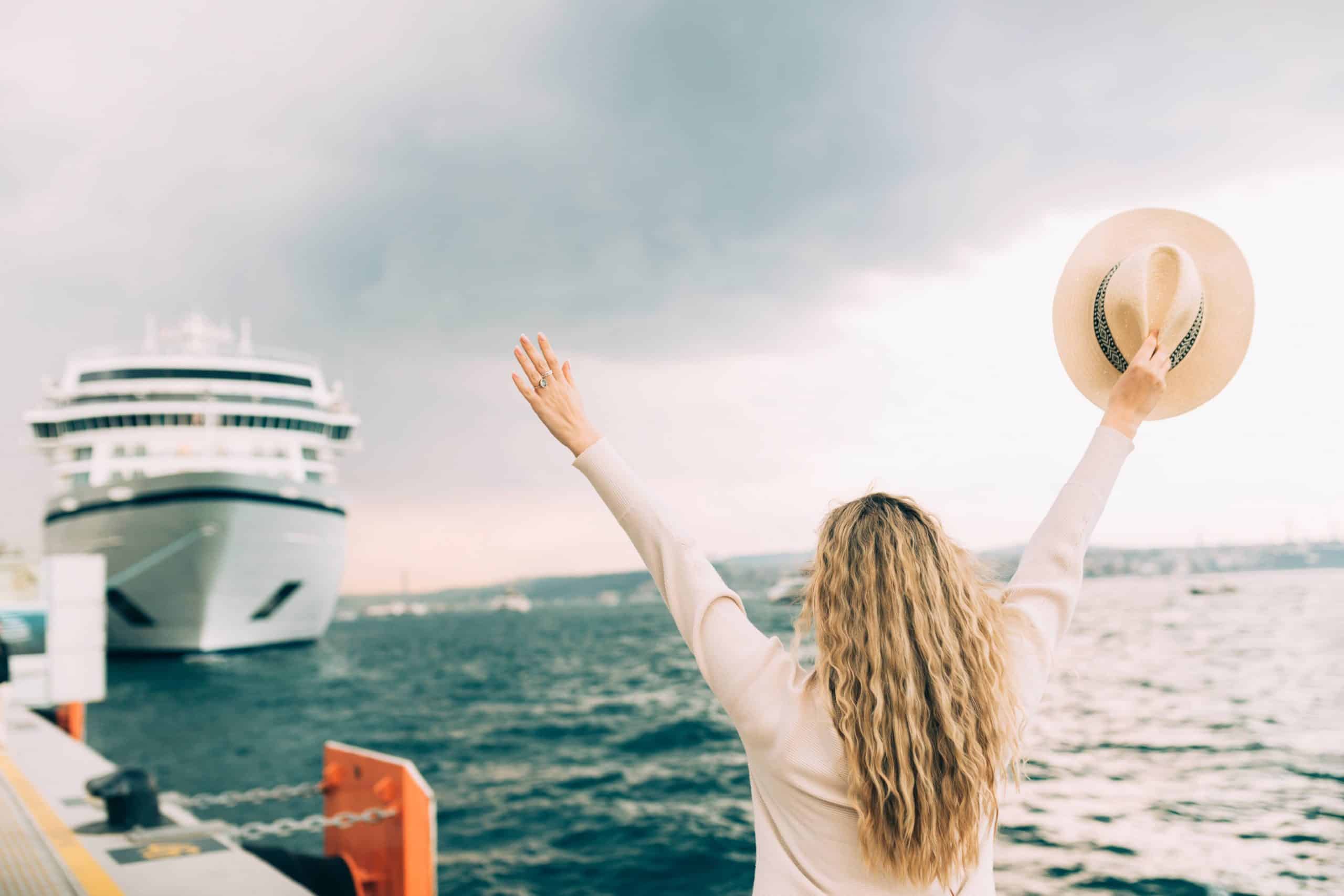 Woman raising her arms while boarding a cruise ship at the port