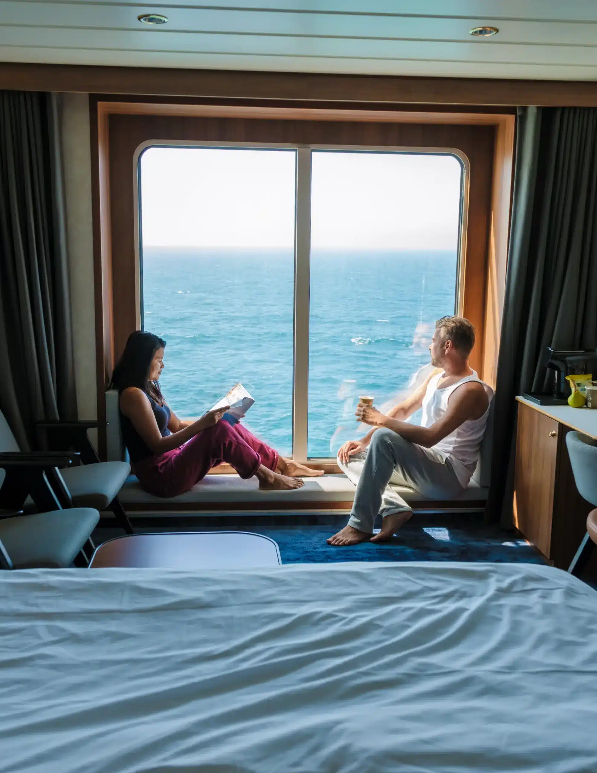 man and woman looking out a cruise cabin window